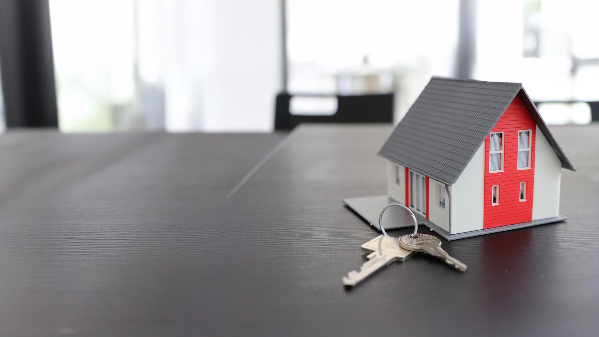 Hausmodell mit Schlüssel auf einem Tisch – Informationen zum FTTH Glasfaseranschluss für Hauseigentümer in Obersiggenthal und Untersiggenthal von Siggenthal4net